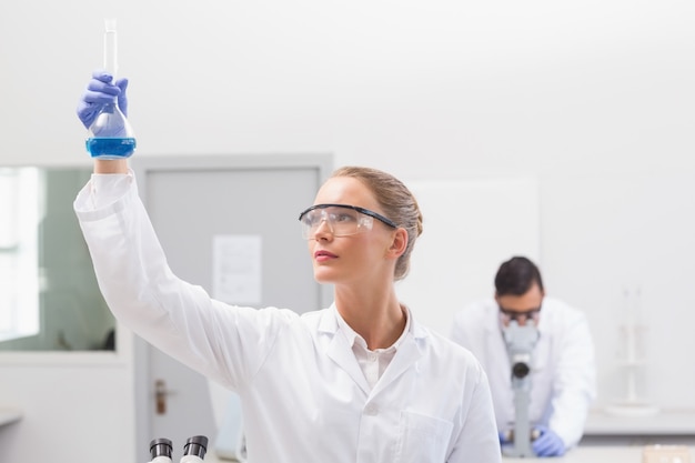 Scientist examining blue precipitate in baker 