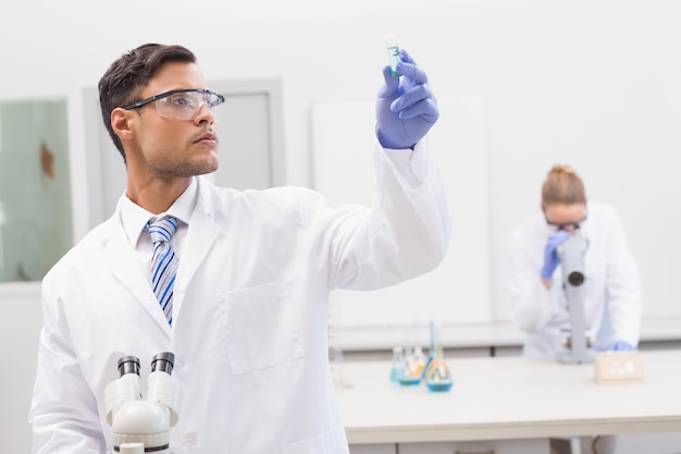 Scientist examining blue precipitate in tube 