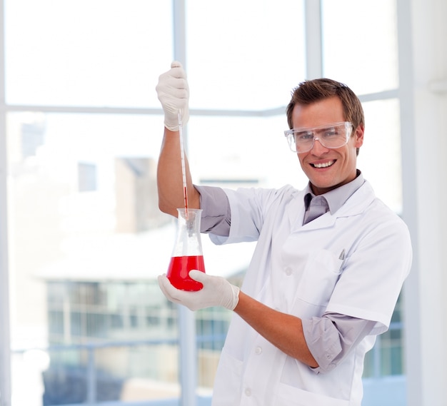 Scientist examining a test-tube looking at the camera