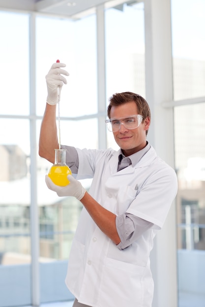 Scientist examining a test-tube looking at the camera