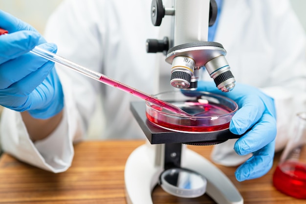 Scientist holding erlenmeyer flask conical flask glassware with red color liquid solution in science chemistry laboratory