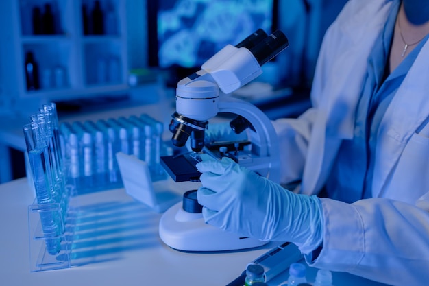 Photo scientist is using microscope in laboratory chemical researcher works in chemistry with concentration chemist is conducting a science experiment using a microscope to test experimental substances