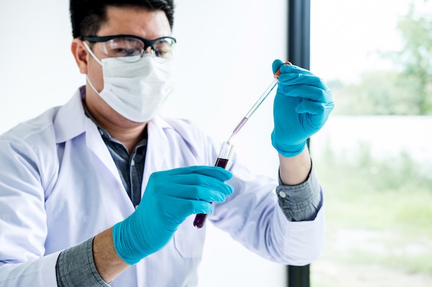 Scientist or medical in lab coat holding test tube with reagent with drop of color liquid