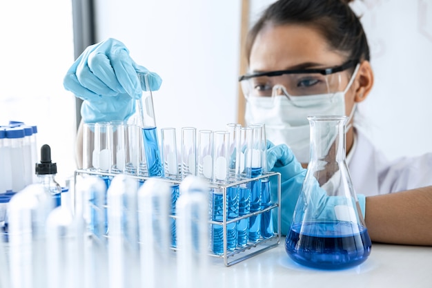 Scientist or medical in lab coat holding test tube with reagent