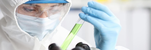 Scientist in protective suit holds test tube with poisonous liquid hazardous chemicals