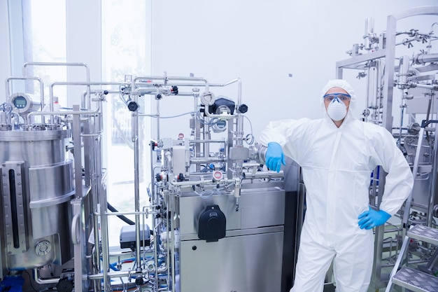 Scientist in protective suit leaning against machine