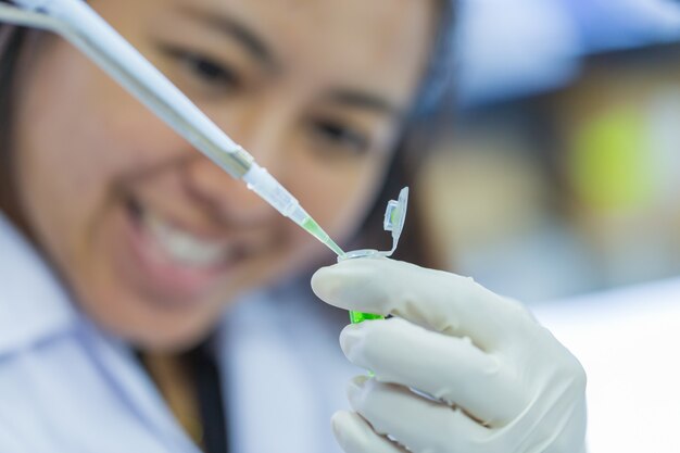 Scientist with pipette and test tube, examining samples and liquid in laboratory