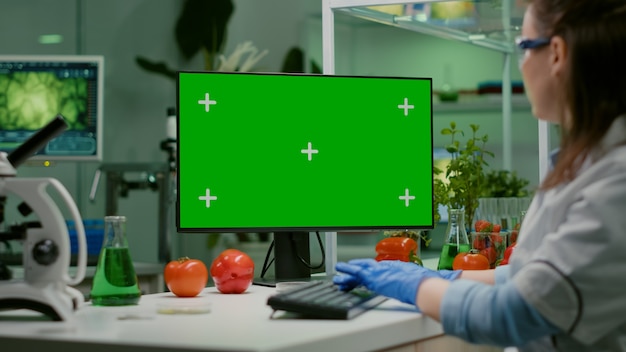 Scientist woman working on computer with mock up green screen