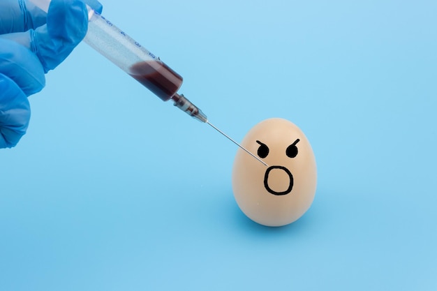 A scientists hand with a syringe makes an injection into the egg Vaccination and treatment of pregnant women