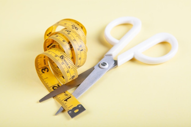 Scissor cuts measuring tape on yellow background