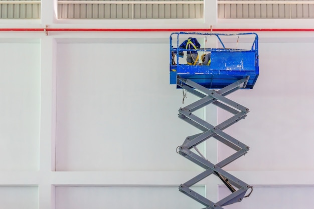 Scissor lift platform with hydraulic system elevated towards a factory roof 