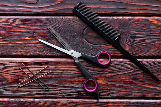 Scissors and comb hairdresser tools on a wooden background