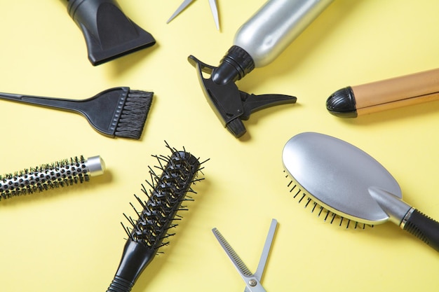 Scissors comb and other hair styling tools on yellow background