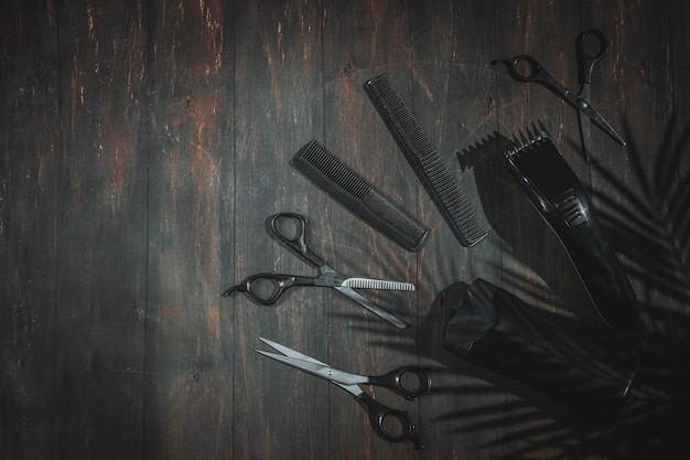 Scissors combs shampoo and men's hair clipper lie on the right on a black