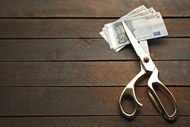 Scissors cut euro banknotes on wooden background