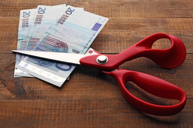 Scissors cuts euro banknote on wooden background