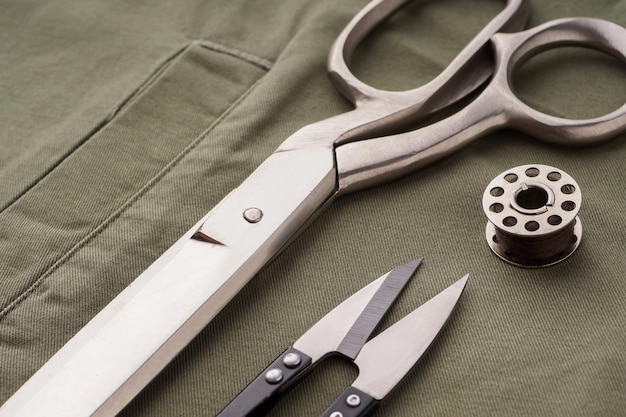 Scissors needles spools of thread a rasparyvatel are laid out on a sewn shirt closeup