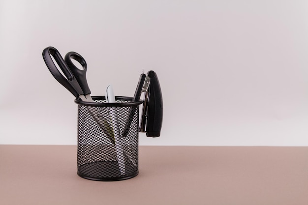 Scissors and a stapler with a handle in an organizer on a white office table