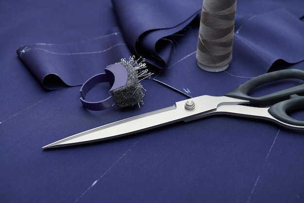 Scissors and tailor tools on blue fabric Clothes sewing Clothing repair Tailoring Close up view