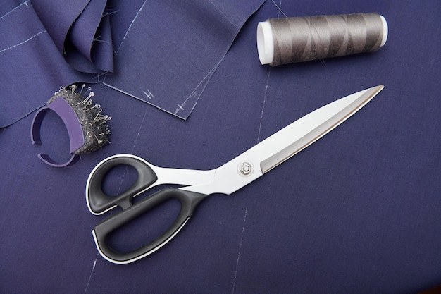 Scissors and tailor tools on blue fabric Fabric cutting Clothes sewing Clothing repair Tailoring Close up view Top view