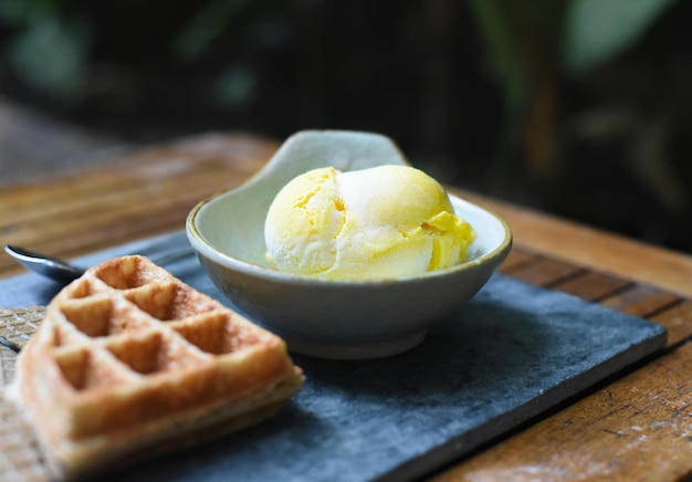 Scoop of mango organic ice cream  in a ceramic bowl on stone gray plate