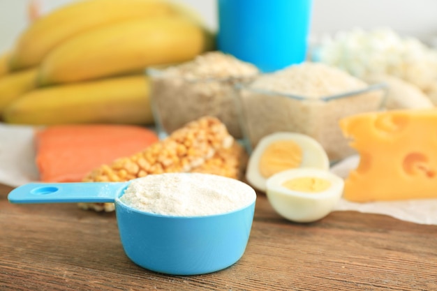 Scoop with protein powder and products on table closeup