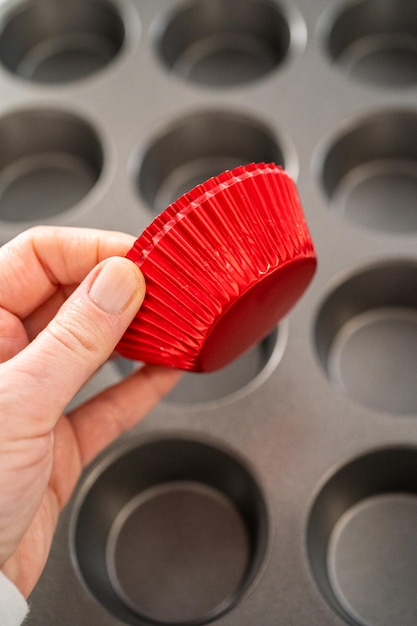 Scooping cake batter with dough scoop into cupcake foil liners to bake chocolate peppermint cupcakes.