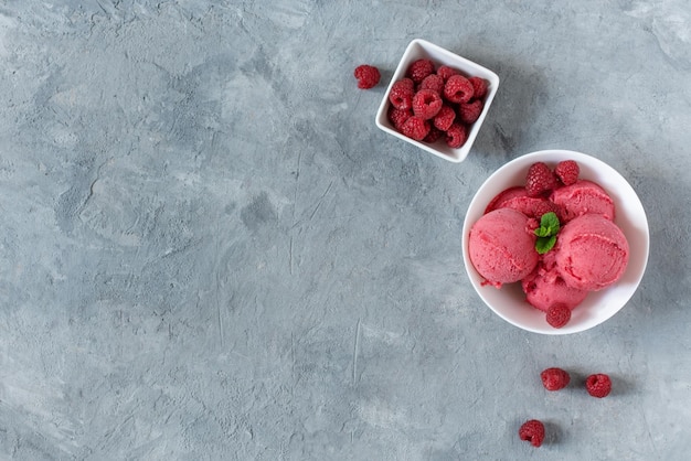 Scoops of raspberry ice cream in a white plate on grey table top view Summer refreshing sorbet