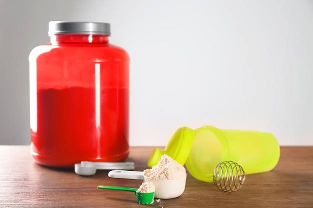 Scoops with protein powder jar and shaker on table