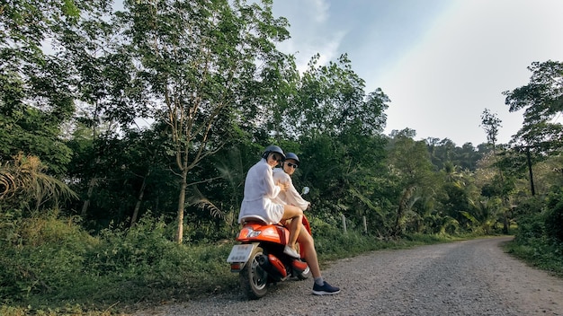 Scooter road trip Love couple on red motorbike in white clothes on forest road trail