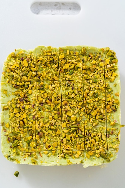 Scoring pistachio fudge using a wheel dough cutter for cutting into small square pieces