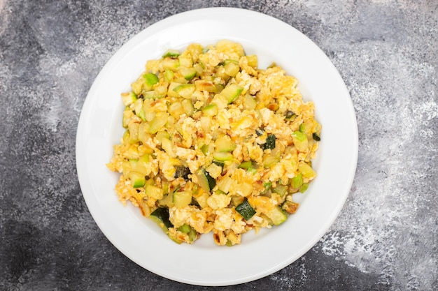 Scrambled egg with zucchini on white small plate