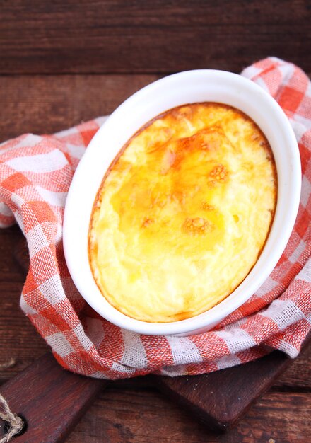 Scrambled eggs baked in white on a dark wooden background