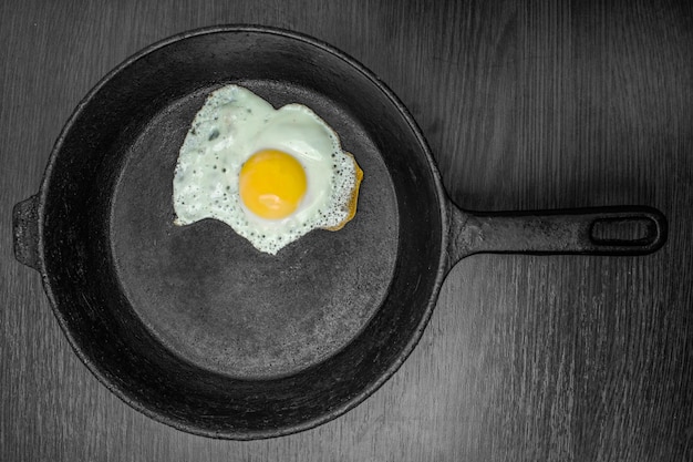 Photo scrambled eggs in a cast iron skillet isolated on dark painted wood from above