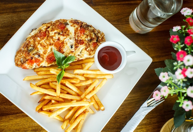 Scrambled eggs and french fries on a wooden table