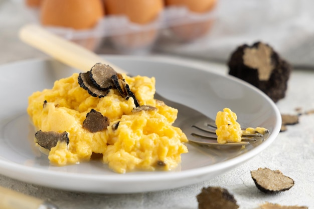 Scrambled eggs with fresh black truffles from Italy served in a plate close up gourmet breakfast