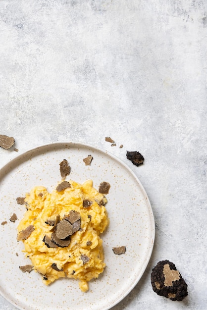 Scrambled eggs with fresh black truffles from Italy served in a plate top view gourmet breakfast