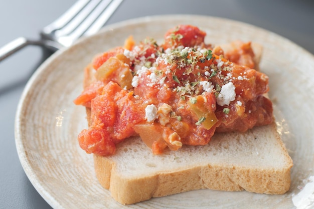 Scrambled eggs with tomato on bun on a plate