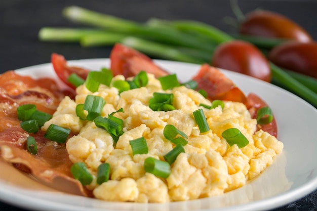 Scrambled eggs with tomatoes on a white plate. on a wooden table