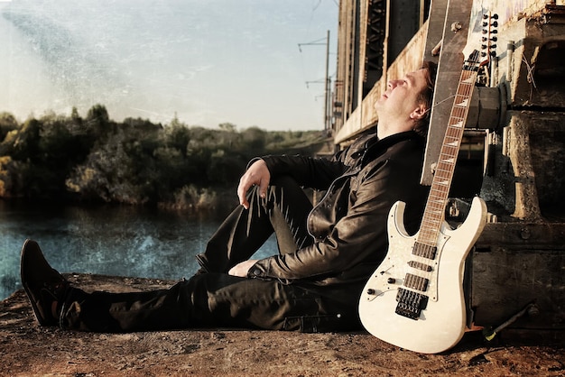 Scratch effect on photo men with guitar on a railroad