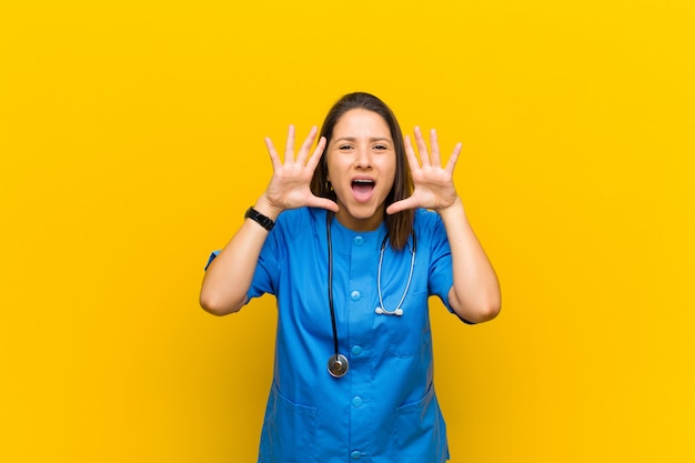 Screaming in panic or anger, shocked, terrified or furious, with hands next to head isolated against yellow wall