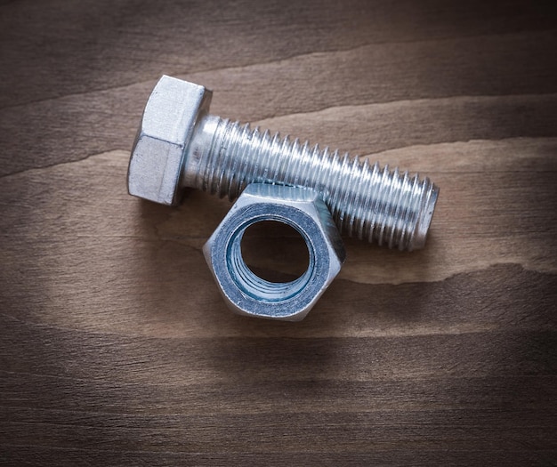 Screwbolt and construction nut on vintage wooden background