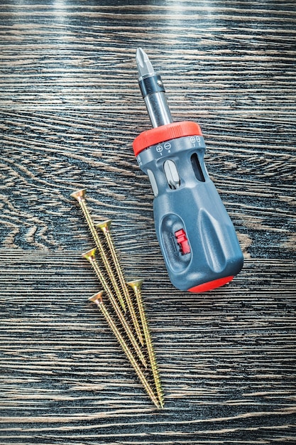 Screwdriver brass screws on wooden board