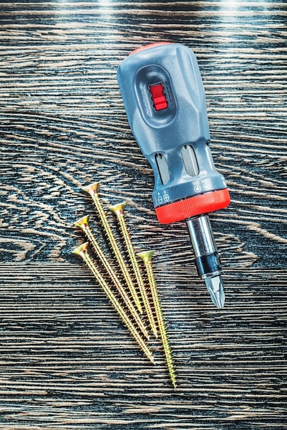 Screwdriver copper screws on wood board top view