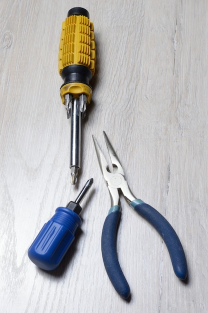 Screwdriver tool and pliers lie on a light-colored countertop.