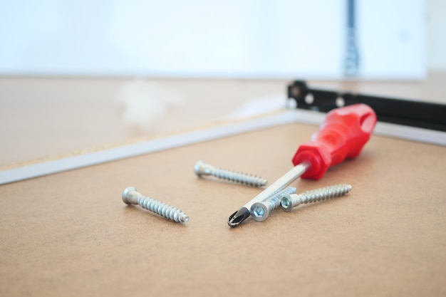 A screwdriver and various screws positioned on a wooden surface for easy access and use