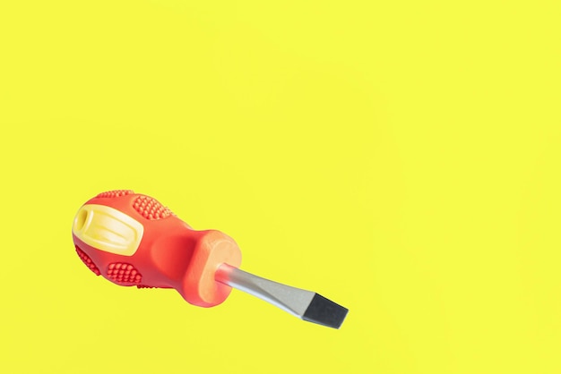 A screwdriver A working tool A flat screwdriver on a yellow background Copy space