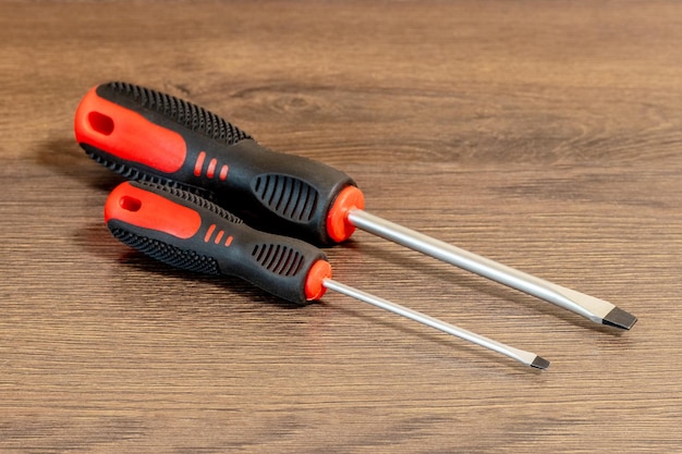 Screwdrivers of different sizes with straight tips on a wooden table