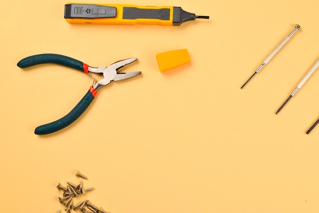 Screwdrivers and pliers on orange background