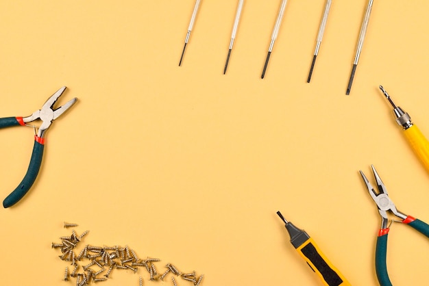 Screwdrivers and pliers on orange background